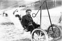 Das Foto zeigt den Motorflieger Hans Grade in schwarz weiß, der in einem alten Motorflieger sitzt